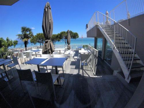 a patio with tables and umbrellas next to the beach at Hotel Ca' Serena in Sirmione