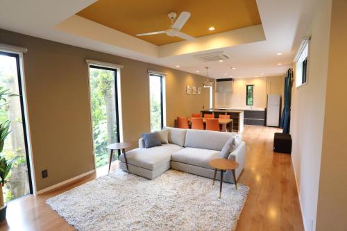 a living room with a white couch and a kitchen at Tabinoteitaku Okinawa Bise HOMANN CONCEPT in Motobu