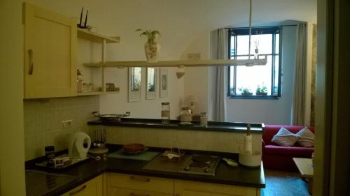オルヴィエートにあるAppartamento per Vacanza La Fontanellaのキッチン(カウンター、赤いソファ付)