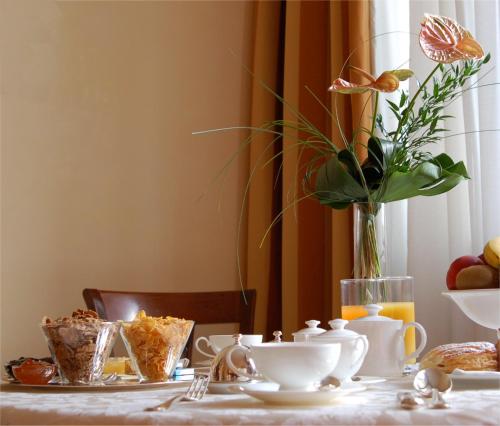 a table with a vase of flowers and food on it at Astoria Hotel Italia in Udine