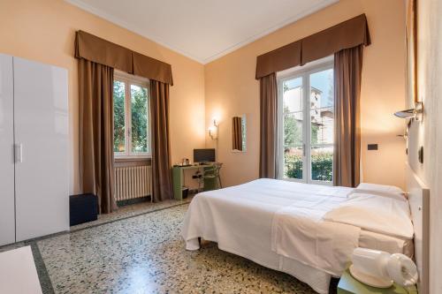 una camera da letto con un grande letto bianco e finestre di Lucca In Villa Elisa & Gentucca a Lucca