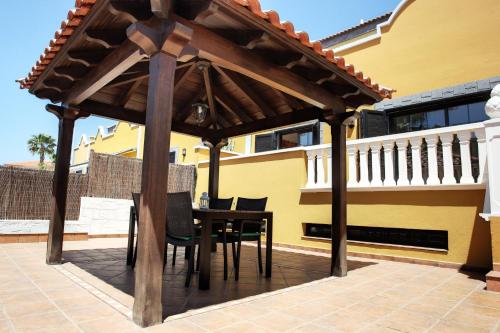 a wooden gazebo with a table and chairs on a patio at Chalet Costa Adeje in Adeje