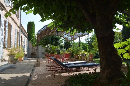 un patio con un banco, mesas y un árbol en Les Passiflores en Grasse