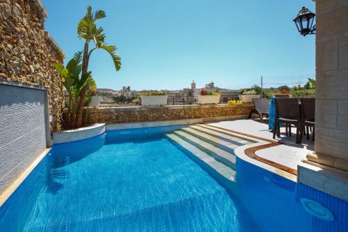 a swimming pool with blue water on a building at Carini Farmhouses in Għarb