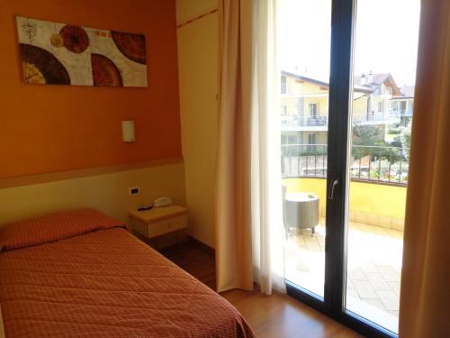 a bedroom with a bed and a door to a balcony at Hotel La Rondine in Sirmione