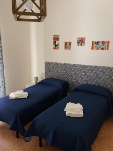 2 Betten in einem Zimmer mit blauer Bettwäsche in der Unterkunft Casa Fiore in Neapel