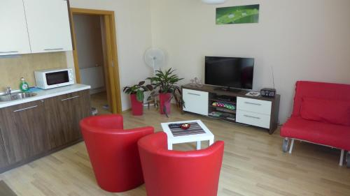 a living room with two red chairs and a tv at Park - apartmány na prenájom in Nové Mesto nad Váhom