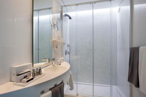 
a bathroom with a shower, sink, and mirror at Hotel White Lisboa in Lisbon
