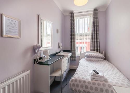 een kleine slaapkamer met een bureau en een bed bij Kingswood Guest House in Stockton-on-Tees