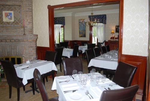 a dining room with white tables and chairs and a mirror at Chez Truchon Bistro-Auberge in La Malbaie