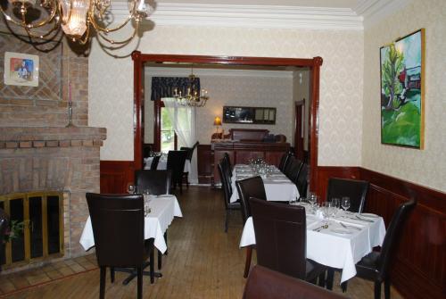 a dining room with white tables and chairs and a fireplace at Chez Truchon Bistro-Auberge in La Malbaie