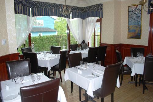 a dining room with white tables and black chairs at Chez Truchon Bistro-Auberge in La Malbaie