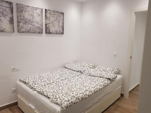 Bett in einem Zimmer mit drei Gemälden an der Wand in der Unterkunft Boliches Apartment in Fuengirola