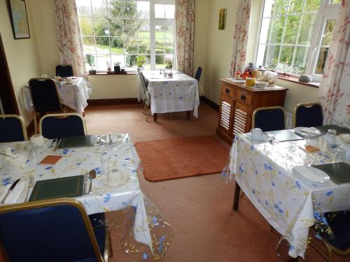 a dining room with two tables and chairs and windows at Meadowfield Bed And Breakfast in Ballyvaughan