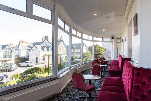 a row of red chairs and tables in a room with windows at The Glendeveor in Newquay