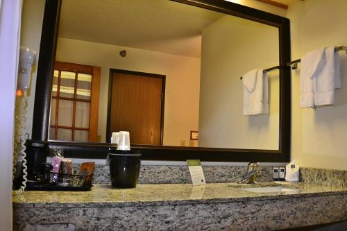 a bathroom with a large mirror and a sink at AmericInn by Wyndham Calumet in Calumet