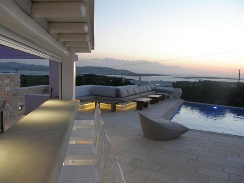 a patio with a pool and chairs and a couch at Anna Platanou Suites in Agia Irini Paros