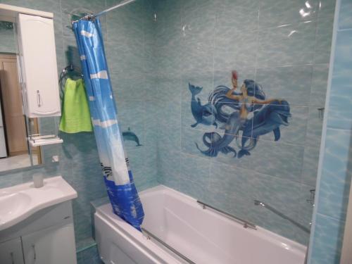 La salle de bains est pourvue d'une baignoire carrelée de bleu et d'un lavabo. dans l'établissement Apartment on Gorkovo 87, à Sotchi