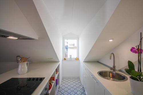 uma cozinha com balcões brancos, um lavatório e uma janela em Apartment Grazioso em Dubrovnik