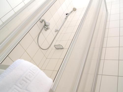 a shower in a white tiled bathroom with a towel at Börse Coswig in Coswig