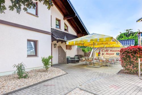 a patio with a table and umbrella next to a building at Cafe Hoyer Pension und Appartements in Rödigsdorf