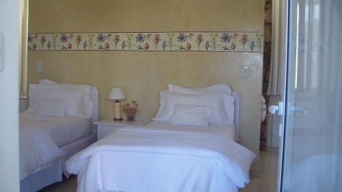 two beds with white sheets and pillows in a bedroom at Hotel Boutique Posada Piedras Blancas in Santa Rosa
