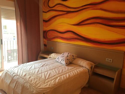 ガンディアにあるApartamento Puerto-Playa Gandiaの壁画が飾られた部屋のベッド1台