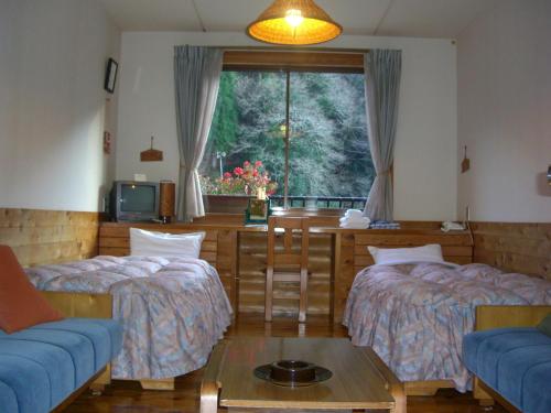 Zimmer mit 2 Betten, einem Tisch und einem Fenster in der Unterkunft Ashita no Mori in Hongu