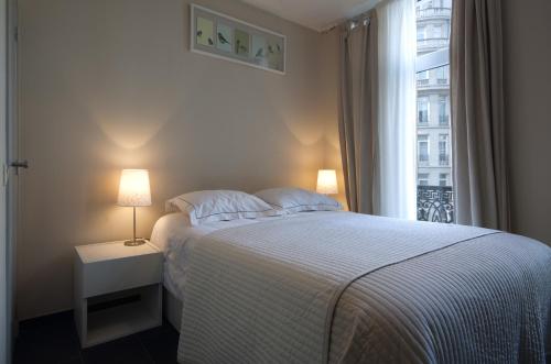 a white bedroom with a bed and a window at Appartbrussels in Brussels