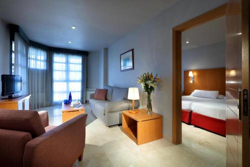 a room with a living room with a bed and a couch at Exe Gran Hotel Almenar in Las Rozas de Madrid