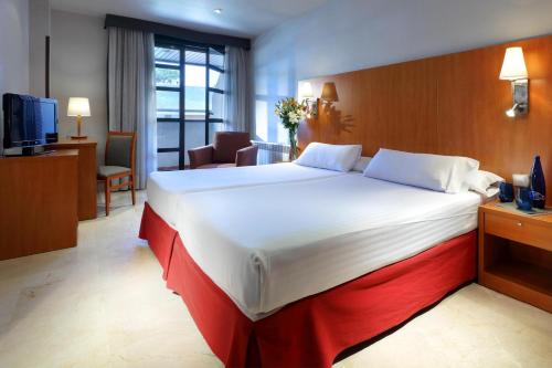 a hotel room with a large bed and a television at Exe Gran Hotel Almenar in Las Rozas de Madrid