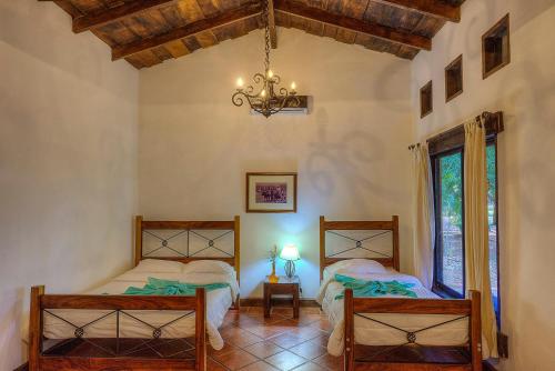 a bedroom with two beds and a chandelier at Hotel Hacienda La Pacifica in Cañas