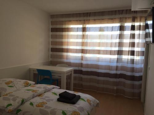 Un dormitorio con una cama y una mesa y una ventana. en Studio Lora G 031, en Saint-Louis