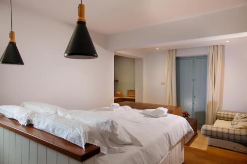 a bedroom with a white bed and a couch at Lithos Guesthouse Kardamili in Kardamili