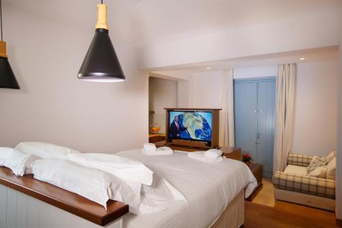 a bedroom with a bed with white sheets and a tv at Lithos Guesthouse Kardamili in Kardamili