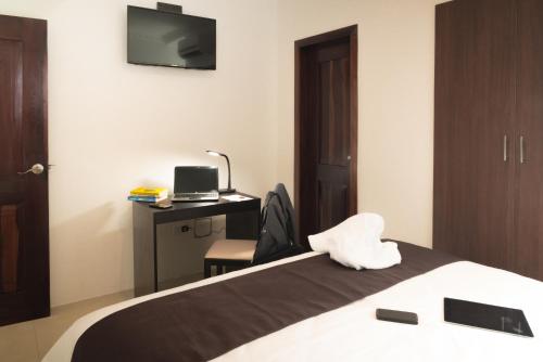 a bedroom with a bed and a desk with a television at Hotel La Ría Playas in Playas