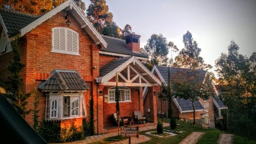 a brick house with a gambrel roof at Chalé Da Colina I in Monte Verde