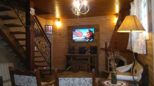 a living room with a television on a wall at Chalé Da Colina I in Monte Verde