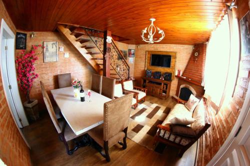 a dining room with a table and chairs and a staircase at Chalé Da Colina I in Monte Verde