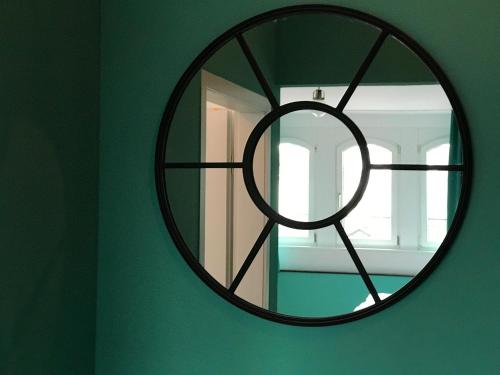 a circular mirror on a green wall with a window at SmartHotel Mystique Self check-in in Bad Homburg vor der Höhe