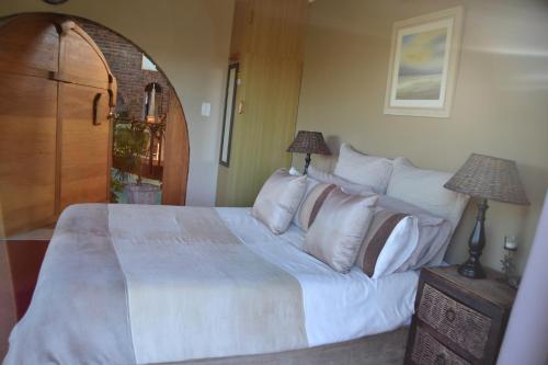 a bedroom with a large bed with white sheets and pillows at Dolphin View Guesthouse in Jeffreys Bay