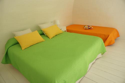 2 letti con lenzuola verdi e arancioni in una stanza di Dante Home - Bari Centro a Bari