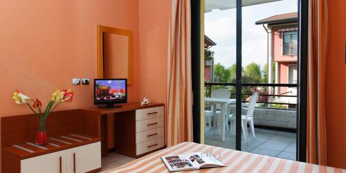 a bedroom with a bed and a television and a balcony at Residence Spiaggia D'Oro in Desenzano del Garda