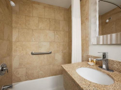 a bathroom with a sink and a tub and a mirror at Days Inn by Wyndham - Cape Cod in West Yarmouth