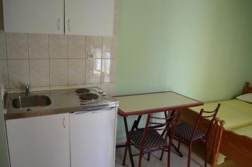 een keuken met een wastafel en een tafel met stoelen bij Guest House Djurovic in Sutomore