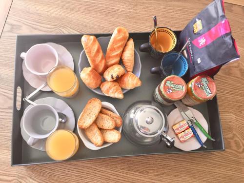 a tray of breakfast food with cups of orange juice and croissants at Les Villas MarInCelu in Porto Pollo