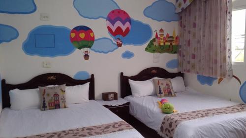 a bedroom with two beds with hot air balloons on the wall at Mei Di Ya House in Yuli
