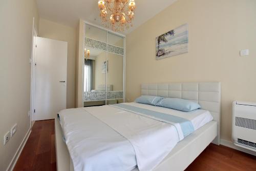 Un dormitorio con una cama blanca y una lámpara de araña. en Luxury Apartments Mia, en Budva