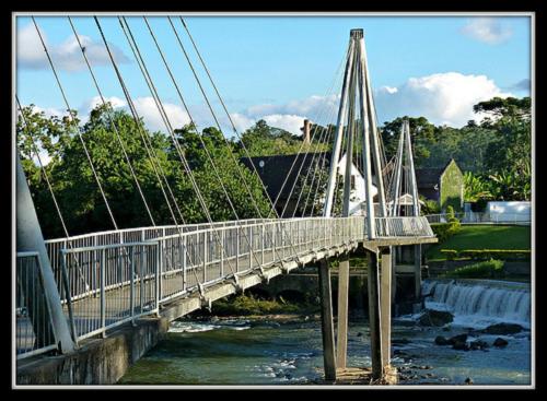 a bridge over a river with a waterfall at Blue Hill Hotel in Timbó