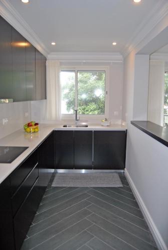 a kitchen with black and white counters and a window at Apartamentos 3 Praias in Ponta Delgada